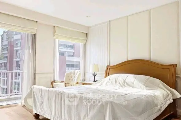 Bright and airy bedroom with large windows and elegant furnishings.