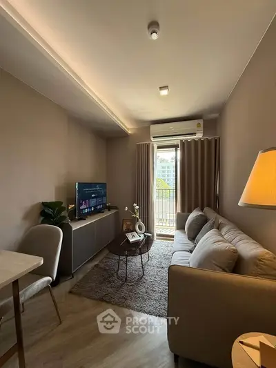 Cozy living room with modern decor, featuring a comfortable sofa, TV, and balcony access.