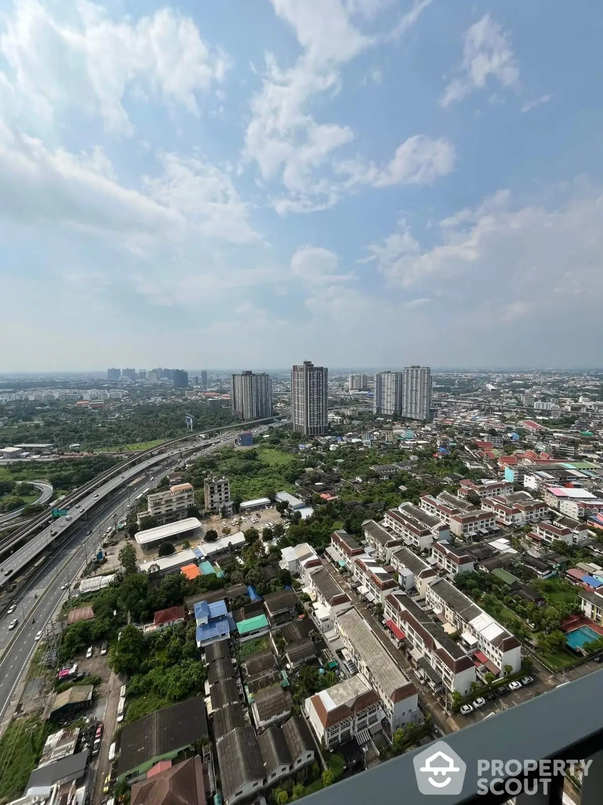 Stunning cityscape view from high-rise balcony overlooking urban skyline and lush greenery.