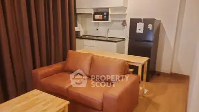 Cozy living room with brown leather sofa and compact kitchen area