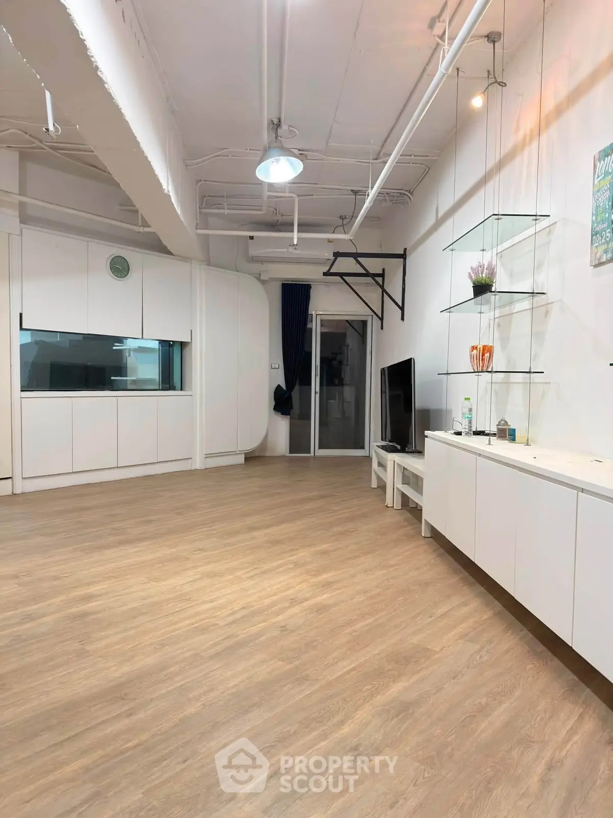 Spacious modern living room with sleek wooden flooring and stylish built-in storage.