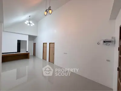 Spacious modern living room with high ceilings and elegant lighting fixtures.