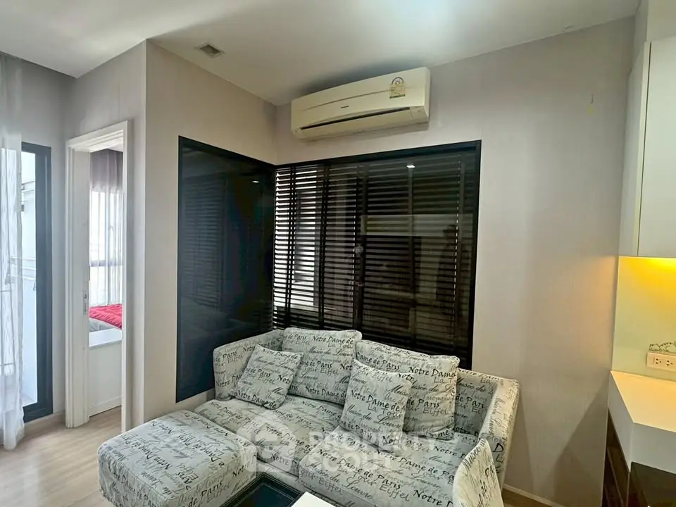 Modern living room with stylish sofa and air conditioning, adjacent to a cozy bedroom.
