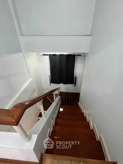 Elegant wooden staircase with modern railing and window curtain