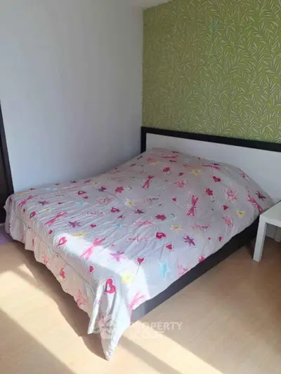Cozy bedroom with floral bedding and green accent wall, perfect for a peaceful retreat.