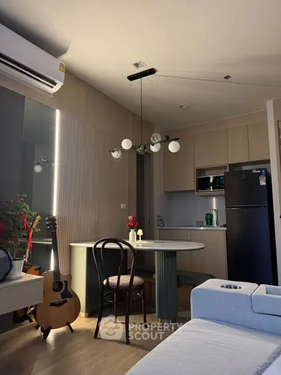 Modern living room with stylish kitchen and cozy dining area, featuring a guitar and elegant lighting.