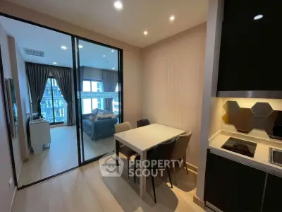 Modern apartment interior with open kitchen and dining area, featuring a view into a stylish bedroom.