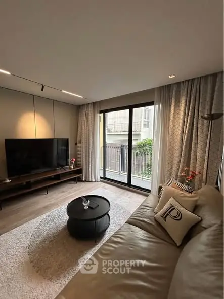 Modern living room with large TV, cozy sofa, and balcony view