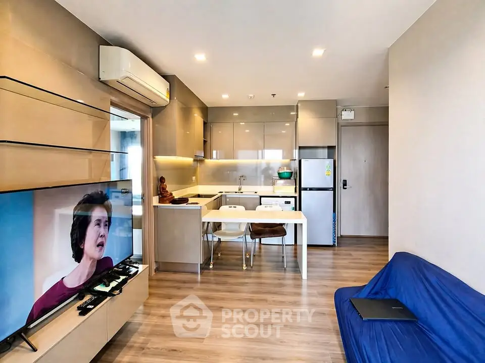 Modern open-layout living room with kitchen, featuring sleek design and cozy ambiance.
