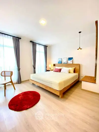 Spacious and bright bedroom with modern decor and large windows.