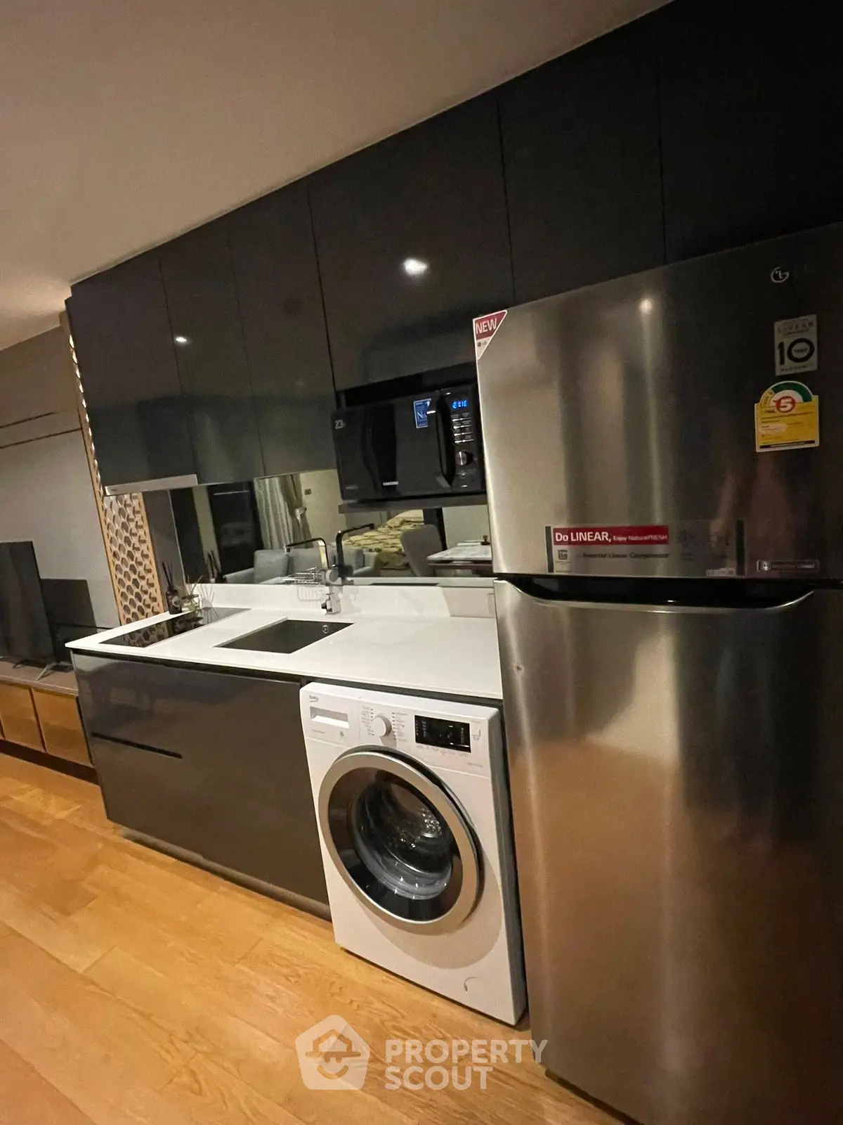 Modern kitchen with sleek cabinets, washing machine, and stainless steel fridge in a stylish apartment.