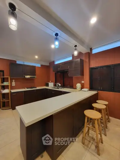 Spacious modern kitchen with island and bar stools, featuring sleek cabinetry and ambient lighting.