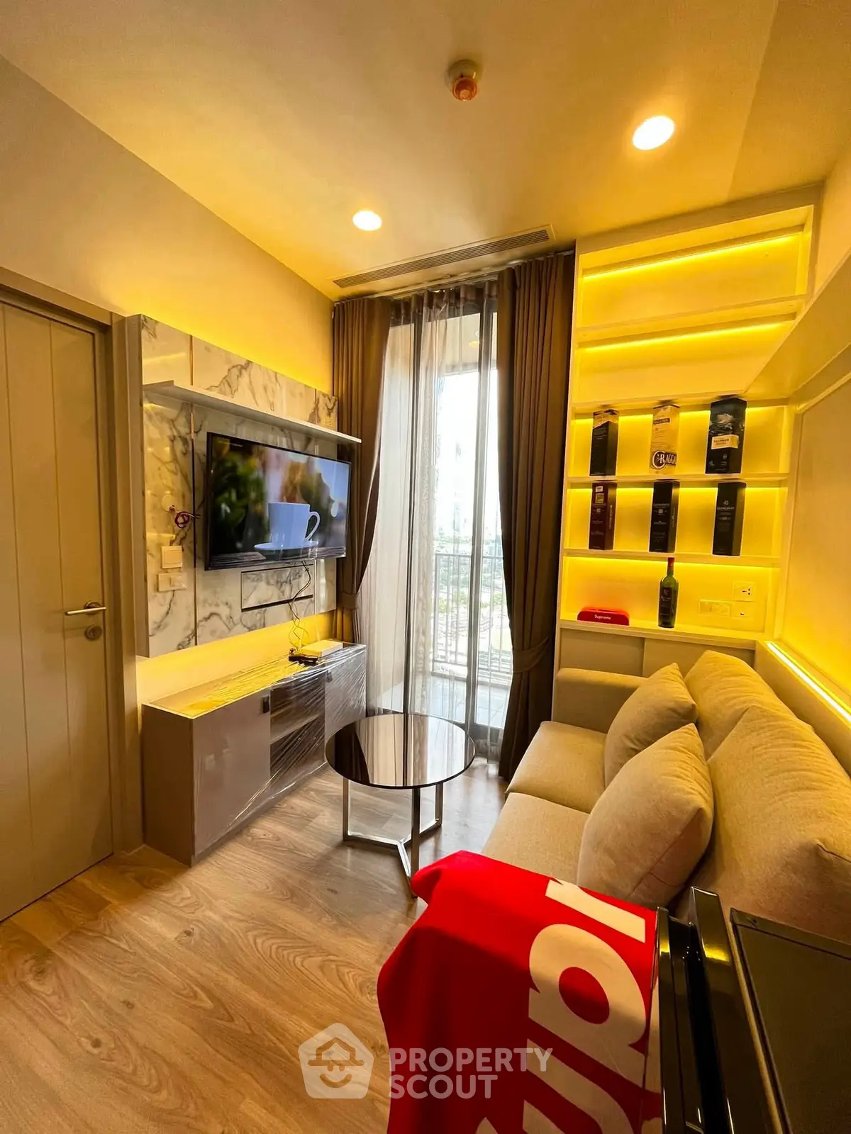 Modern living room with cozy sofa, wall-mounted TV, and stylish shelving in a bright apartment.