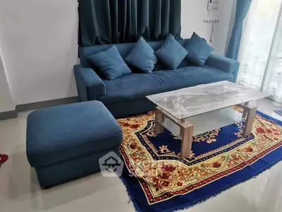 Stylish living room with blue sofa, ottoman, and elegant rug under a sleek coffee table.