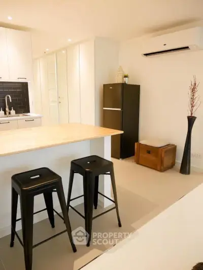 Modern kitchen with island, stools, and sleek appliances in a stylish apartment.