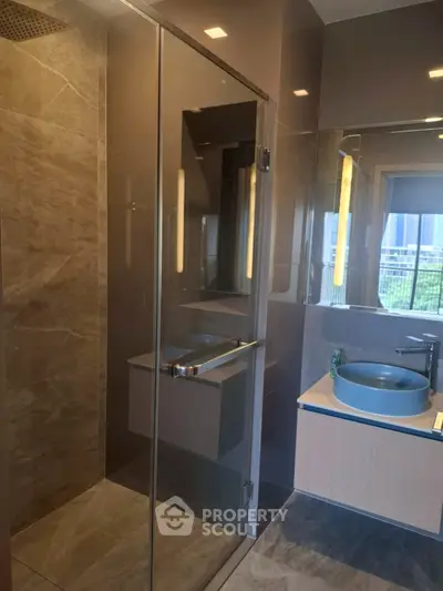 Modern bathroom with glass shower and stylish sink in luxury apartment.