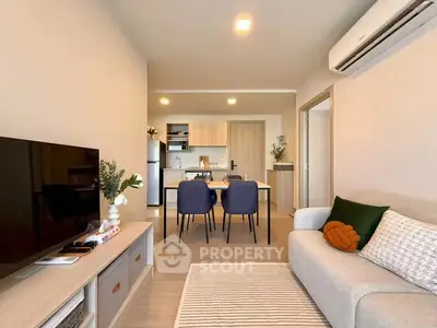 Modern living room with cozy sofa, TV, and dining area in open layout apartment.