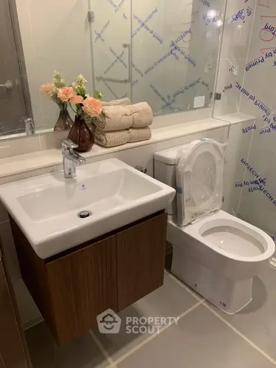 Modern bathroom with sleek sink, toilet, and floral decor in a stylish real estate property.