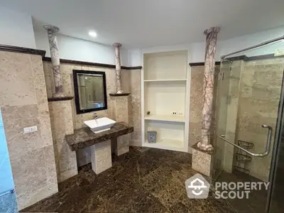 Luxurious marble bathroom with elegant columns and glass shower enclosure