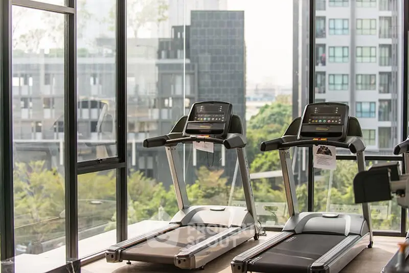 Modern gym with treadmills and city view in luxury apartment building.