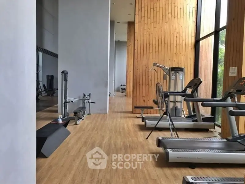 Modern gym with state-of-the-art equipment and wooden accents in a luxury building.