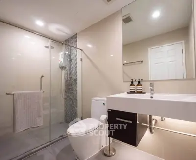 Modern bathroom with glass shower and sleek fixtures in a contemporary home.