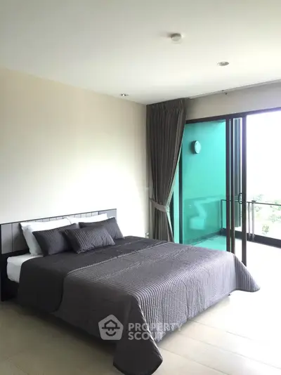 Spacious bedroom with modern design, large bed, and access to a private balcony with natural light flooding through floor-to-ceiling glass doors.
