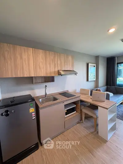 Modern compact kitchen with sleek cabinetry and integrated appliances in cozy apartment.