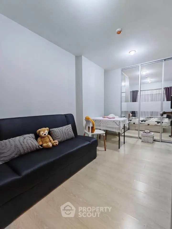 Modern living room with sleek sofa and mirrored wardrobe in a cozy apartment.