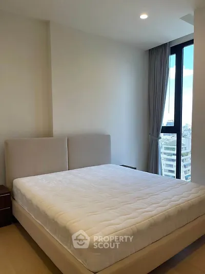 Modern bedroom with large window offering city view, featuring a comfortable bed and sleek design.