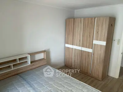 Modern bedroom with wooden wardrobe and bed frame, minimalist design.