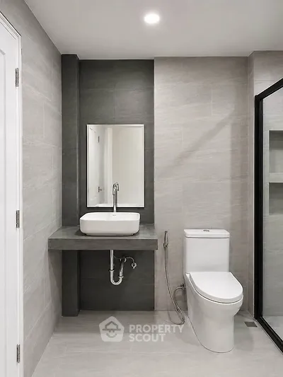 Modern bathroom with sleek design, featuring a wall-mounted sink and contemporary toilet.