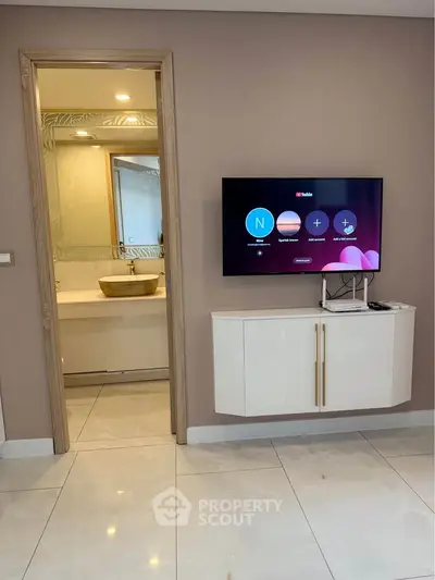 Modern living room with wall-mounted TV and view into elegant bathroom