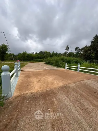 Scenic view of a newly constructed bridge surrounded by lush greenery and cloudy sky.