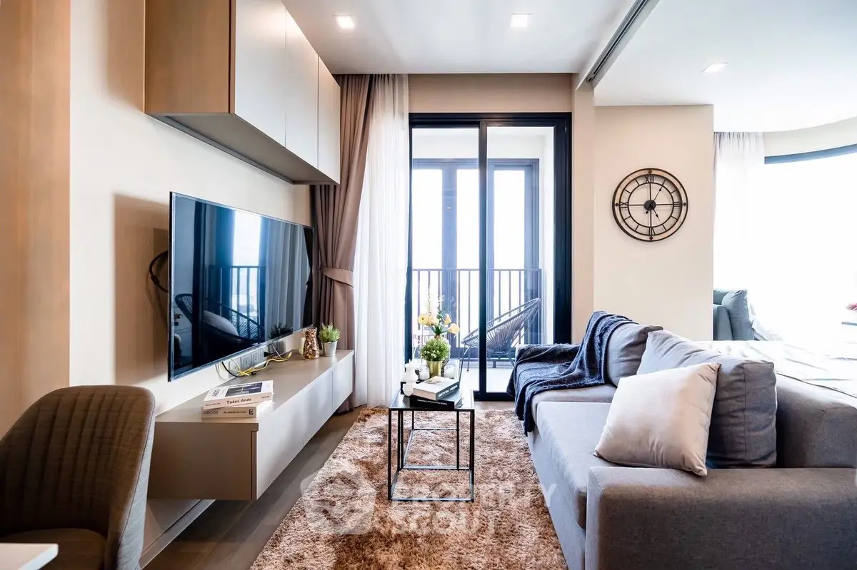 Elegant living room with plush sofa, modern entertainment unit, and balcony access, bathed in natural light for a cozy, upscale living experience.