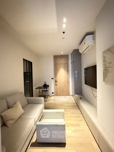 Modern living room with sleek design, featuring a cozy sofa, wall-mounted TV, and stylish lighting.