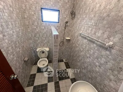 Compact bathroom with tiled walls, shower, and toilet in a cozy real estate property.