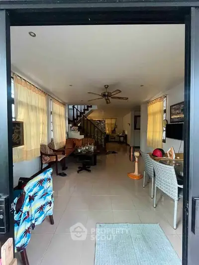 Spacious living room with modern decor and ceiling fan, perfect for family gatherings.