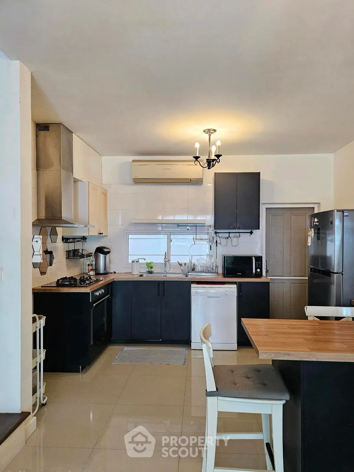 Modern kitchen with sleek black cabinets, wooden countertops, and stainless steel appliances.
