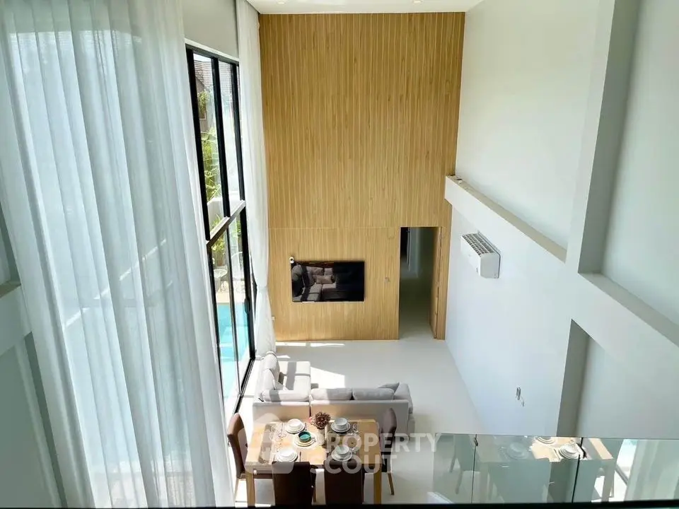 Modern living room with high ceiling and pool view, featuring elegant dining area and large windows.