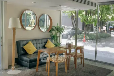 Stylish living room with modern furniture and large windows offering a lush garden view.