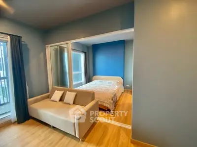 Modern bedroom with cozy sofa and wooden flooring, featuring a stylish blue accent wall.