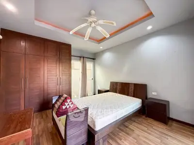Spacious bedroom with wooden furniture and ceiling fan in modern apartment