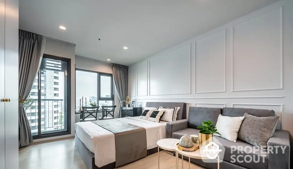 Spacious and modern living room with plush seating, elegant decor, and access to a sunlit balcony with an urban view, perfect for relaxation and entertaining guests.