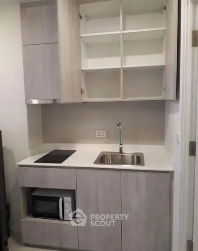 Modern compact kitchen with sleek cabinetry and built-in appliances in a stylish apartment.