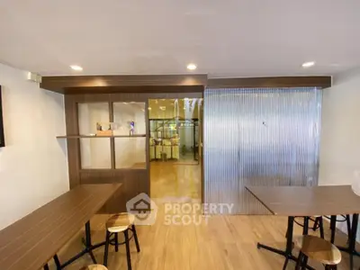 Spacious modern kitchen with sleek wooden countertops, ample seating, and a semi-transparent partition for a bright, open feel.