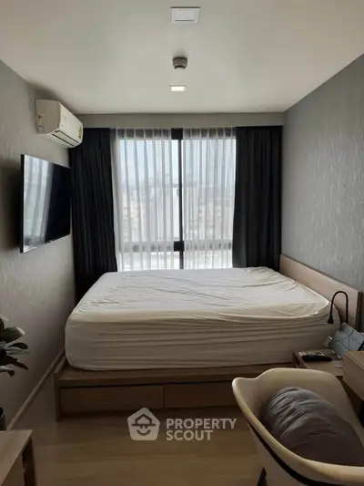 Modern bedroom with large window and sleek furnishings in a stylish apartment.
