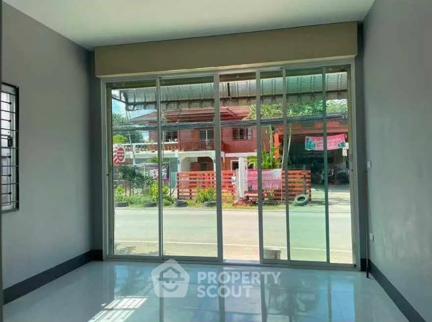Spacious room with large glass doors offering street view, perfect for natural light.
