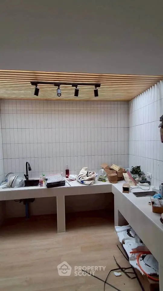 Modern kitchen under renovation with sleek wooden ceiling and tiled walls