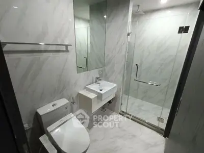 Modern bathroom with glass shower and sleek fixtures in contemporary design.